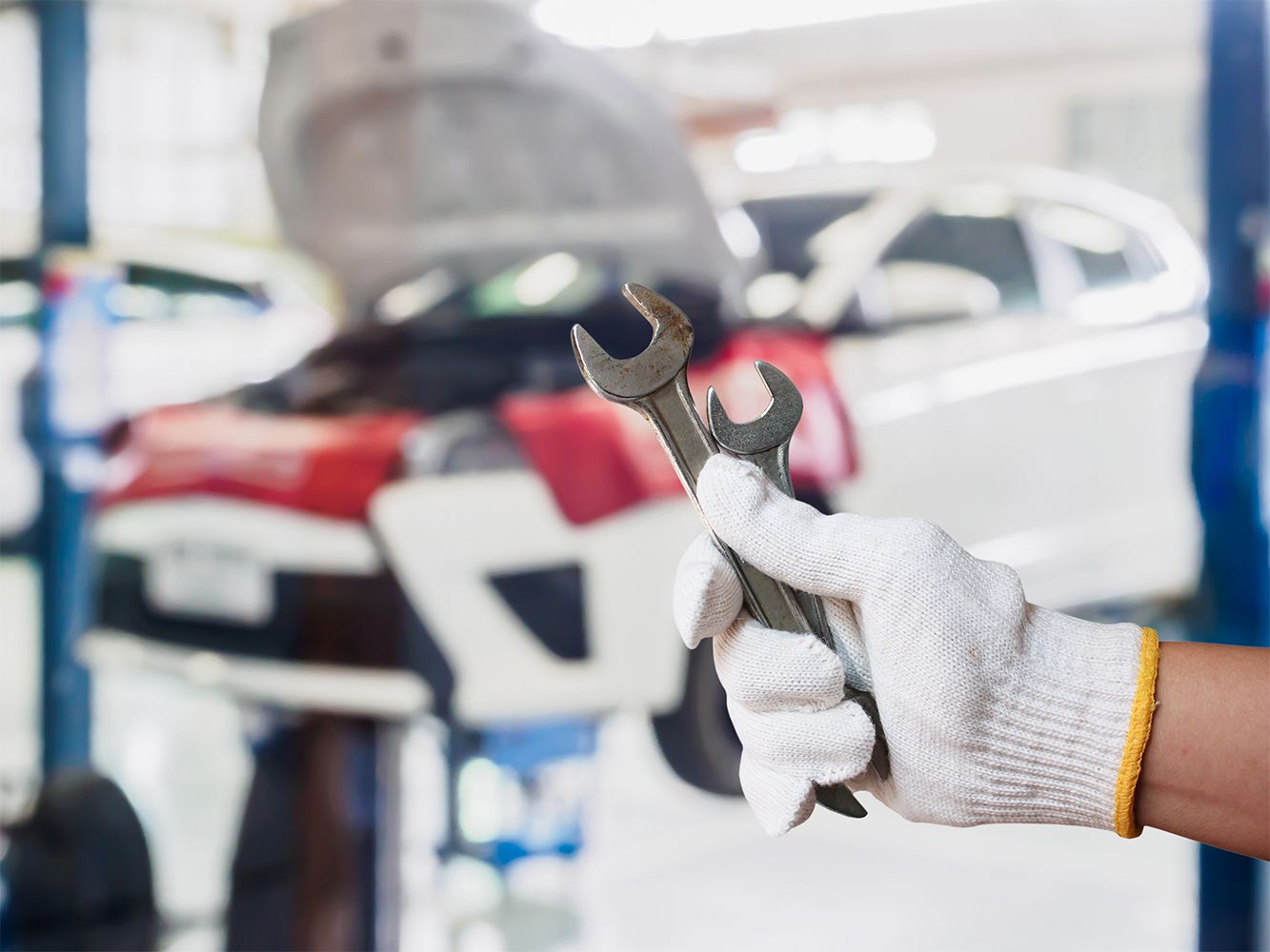 Ein KFZ-Mechaniker hält zwei Schraubenschlüssel in der Hand.